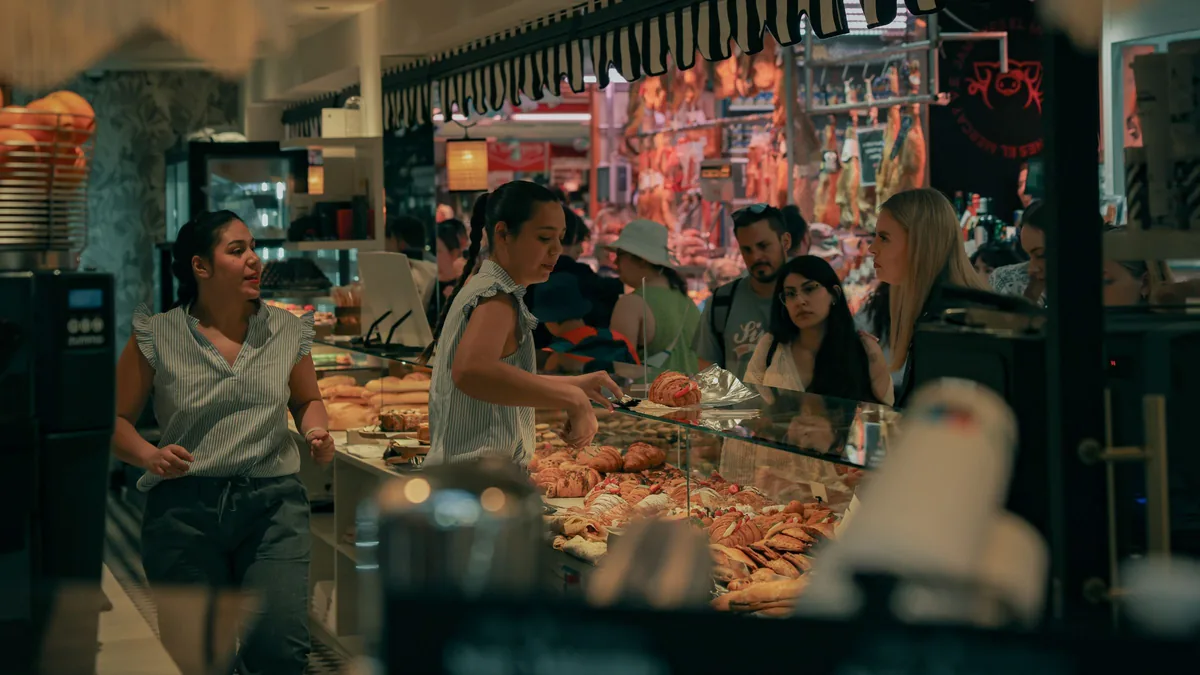 Mostrador de una panadería de mercado con el género ordenado y clientes esperando