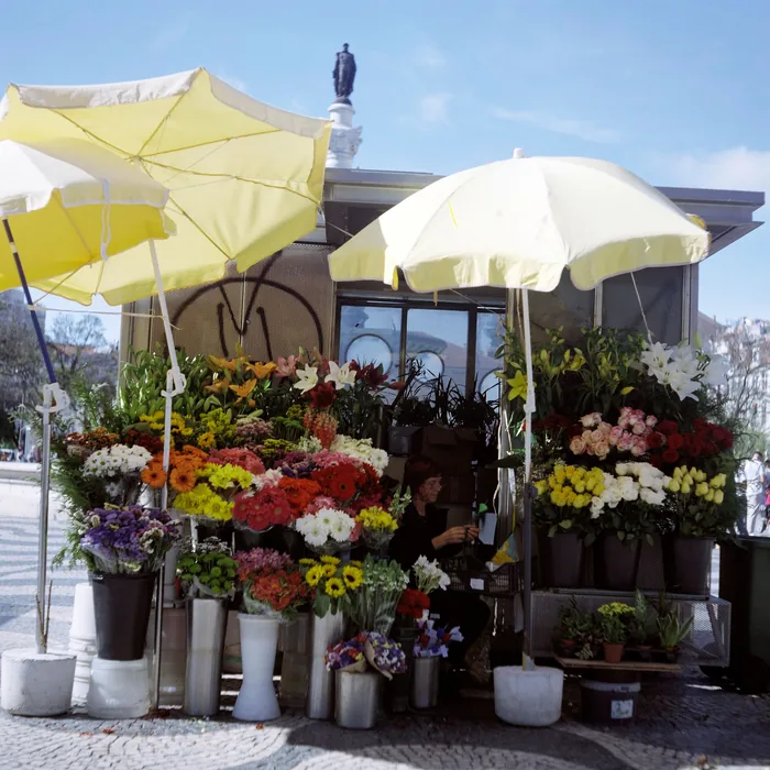 Puesto de flores con los ramos preparados bajo sombrillas amarillas